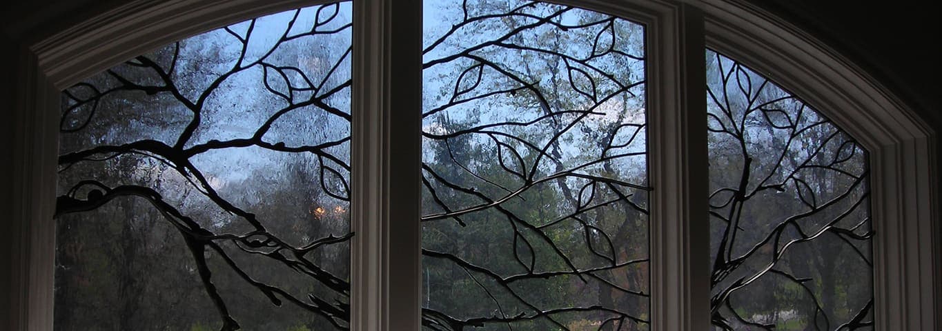 Leaded art glass window with a tree-branch design against the sky